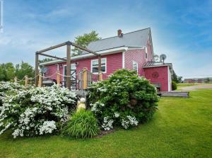Belle River的住宿－Welcome to Pinette House，院子里的红色房子,鲜花盛开