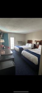 a hotel room with three beds and a window at Islander Inn in Put-in-Bay