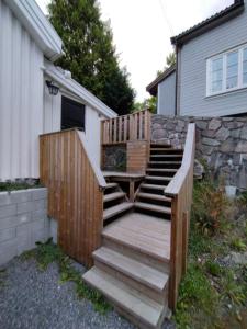 a wooden staircase next to a house with a stone wall at Sørlandshus med 3 soverom in Arendal