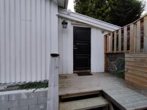 eine Holzveranda mit einer schwarzen Tür an einem Haus in der Unterkunft Sørlandshus med 3 soverom in Arendal
