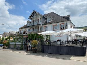 un edificio con mesas y sombrillas delante en Hotel Zum Anker, en Neumagen-Dhron