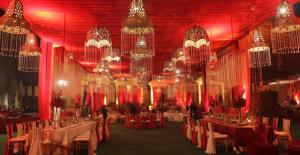 uma grande sala cheia de mesas e lustres em Q Palace em Comilla