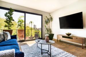 a living room with a tv and a blue couch at Chic PH Haven with rooftop, Condesa 2BR By Tasman in Mexico City