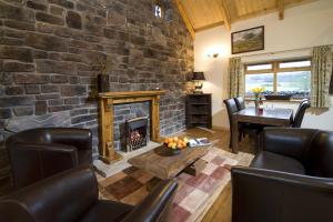 a living room with a stone wall with a fireplace at Clan Cottages Luxury Thatched Retreat near Oban in Oban