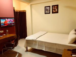 um quarto de hotel com uma cama e uma televisão em Q Palace em Comilla