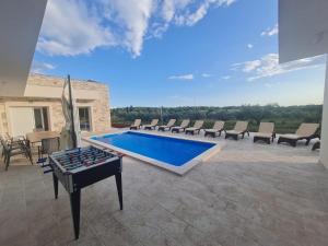 a pool with chairs and a ping pong table on a patio at Villa Mare e Monti with heated pool in Umag