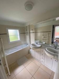 a bathroom with two sinks and a bath tub and a window at Villas du Golf Domaine Royal Green in Pont-de-Larn