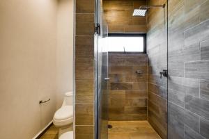 a bathroom with a glass shower with a toilet at Chic PH Haven with rooftop, Condesa 2BR By Tasman in Mexico City +51 photos