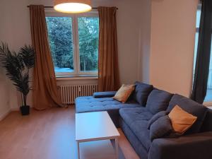 ein Wohnzimmer mit einem blauen Sofa und einem Fenster in der Unterkunft Spacious 70sqm apt in popular location in Düsseldorf