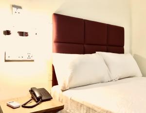 a bed with a phone on a table next to it at Q Palace in Comilla