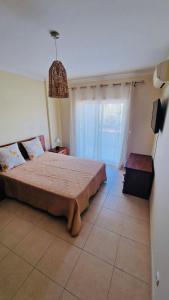um quarto com uma cama e uma grande janela em Sofiamarholidays- Casa levante em Portimão