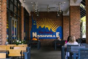 Leute sitzen an Tischen in einem Restaurant mit einem Schild an der Wand in der Unterkunft Sonder at Village 21 in Nashville