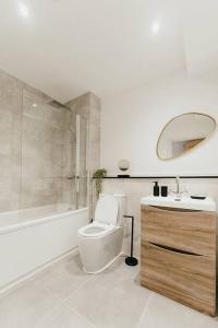 a bathroom with a toilet and a sink and a tub at Pacific Suite - Wyndale Living- BHam JQ Lux 2 BR in Birmingham
