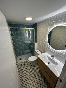 een badkamer met een wastafel, een toilet en een spiegel bij Apartamento en el puerto in Denia