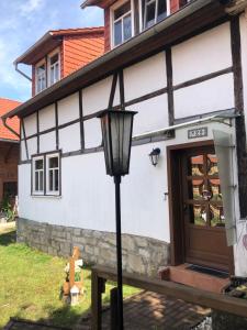 uma casa branca com uma luz de rua em frente em Tannhäuser Hörselhäuschen em Wutha-Farnroda