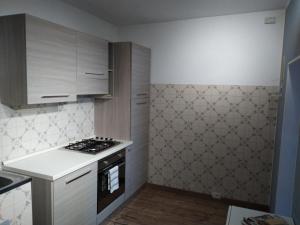 a kitchen with white cabinets and a stove top oven at Venanzio! in Pianello Del Lario
