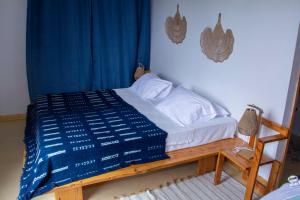 a bedroom with a bed with a blue comforter at Pipi's Guest House in São Filipe