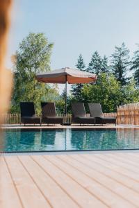 een zwembad met stoelen en een parasol naast bij Wellness Aparthotel "Lechlife" incl Infinity Pool - 400m zum Lift in Reutte