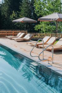 una piscina con tumbonas y sombrillas en Wellness Aparthotel "Lechlife" incl Infinity Pool - 400m zum Lift, en Reutte