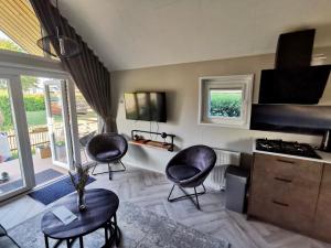 ein Wohnzimmer mit zwei schwarzen Stühlen und eine Küche in der Unterkunft Tiny Haus Auszeit am See in Lathum