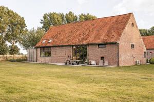 a brick barn with a picnic table in a field at Hoeve-C in Ieper