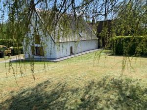 an old white building in a field with a tree at Maison de campagne moderne in Beaurieux