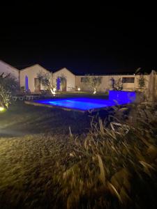 a pool with blue lighting in a yard at night at Masseria Crocco in Montalbano Ionico