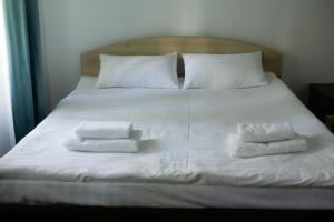 łóżko z białą pościelą i dwoma ręcznikami w obiekcie Mountain View Lodge w mieście Alamedin