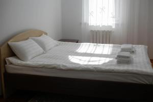 Una cama con sábanas blancas y toallas. en Mountain View Lodge, en Alamedin
