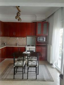 eine Küche mit roten Schränken sowie einem Tisch und Stühlen in der Unterkunft Four Reasons Apts Ampelokipi in Thessaloniki