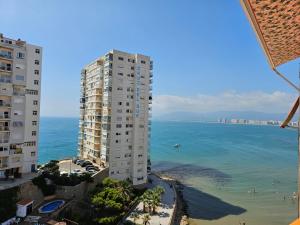 Apartamento a pie de playa I في فارو دي كوييرا: مبنى طويل على الشاطئ بجوار المحيط