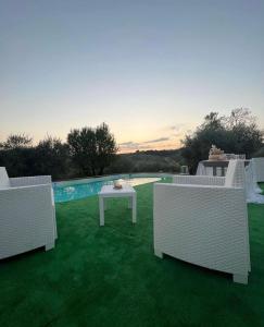 a patio with three chairs and a table on the grass at La massaria di Cesare in Pianella +13 photos