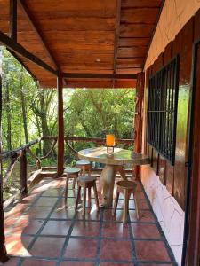 um pátio com uma mesa e bancos num alpendre em Cabañas Lunas del Poás 