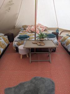 Zimmer mit 3 Betten und einem Tisch in einem Zelt in der Unterkunft Belle tent 2 in Wrexham