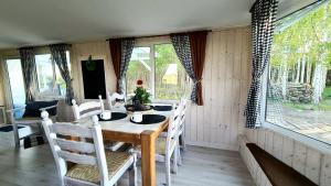 a dining room with a table and chairs and windows at Domki Mierzeja 