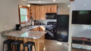 een keuken met een zwarte koelkast en houten kasten bij Brightstone Lake Cabin 1 in Fair Oaks