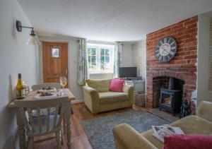 a living room with a brick fireplace and a table and chairs at Flint Cottage in Debenham