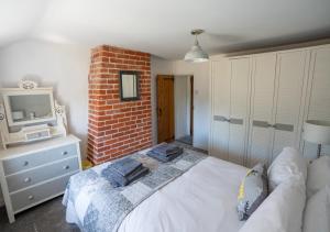 a bedroom with a white bed and a brick wall at Flint Cottage in Debenham