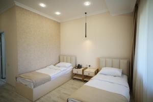 Habitación con 2 camas y mesa con lámpara. en WHITE HOTEL GYUMRI en Gyumri