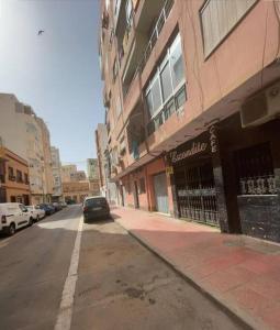 une rue avec une voiture garée à côté d'un bâtiment dans l'établissement Piso a 3 minutos de la playa del zapillo (Almeria), à Almería