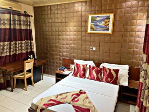 - une chambre avec un lit, une table et un bureau dans l'établissement Hôtel Excelle Xior, à Yaoundé