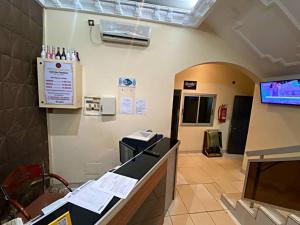 a hospital room with a cash register and a room with a tv at Hôtel Excelle Xior in Yaoundé