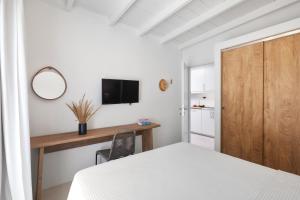 a bedroom with a bed and a desk with a television at Casa Sabbia 10m from the beach in Pelekas