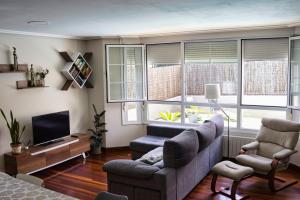 a living room with a couch and a tv and windows at La casuca de Logan in Castro-Urdiales