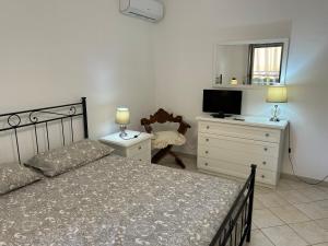 - une chambre avec un lit, une commode et une télévision dans l'établissement Leda House, à Villaggio del Fanciullo
