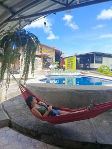 a woman laying in a hammock next to a pool at Hostería Cacique Wasi in Puyo