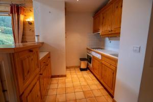 Una cocina con gabinetes de madera y piso de baldosas. en Grand Duc 8, en Méribel