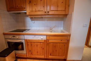 Una cocina con gabinetes de madera y un fregadero. en Grand Duc 8, en Méribel