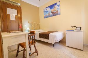 Habitación pequeña con cama, escritorio y escritorio. en Hotel Colón en Ronda