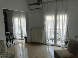 a living room with large windows with white curtains at Four Reasons Apts Ampelokipi in Thessaloniki